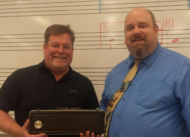 Dr Mike Hess, presenting a flute to band director, Michael Cale.